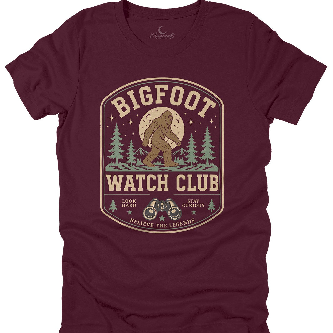A black short-sleeve crewneck t-shirt featuring a vintage-style graphic print of Bigfoot in a tree forest under a full moon, with the text 'BIGFOOT WATCH CLUB' and 'BELIEVE THE LEGENDS'.