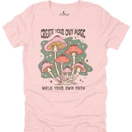 Pink t-shirt with mushroom graphic and text 'Create Your Own Magic, Walk Your Own Path' on a white background