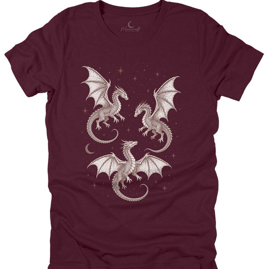 A maroon short-sleeve t-shirt with a graphic print of three white dragons flying amidst stars and a crescent moon