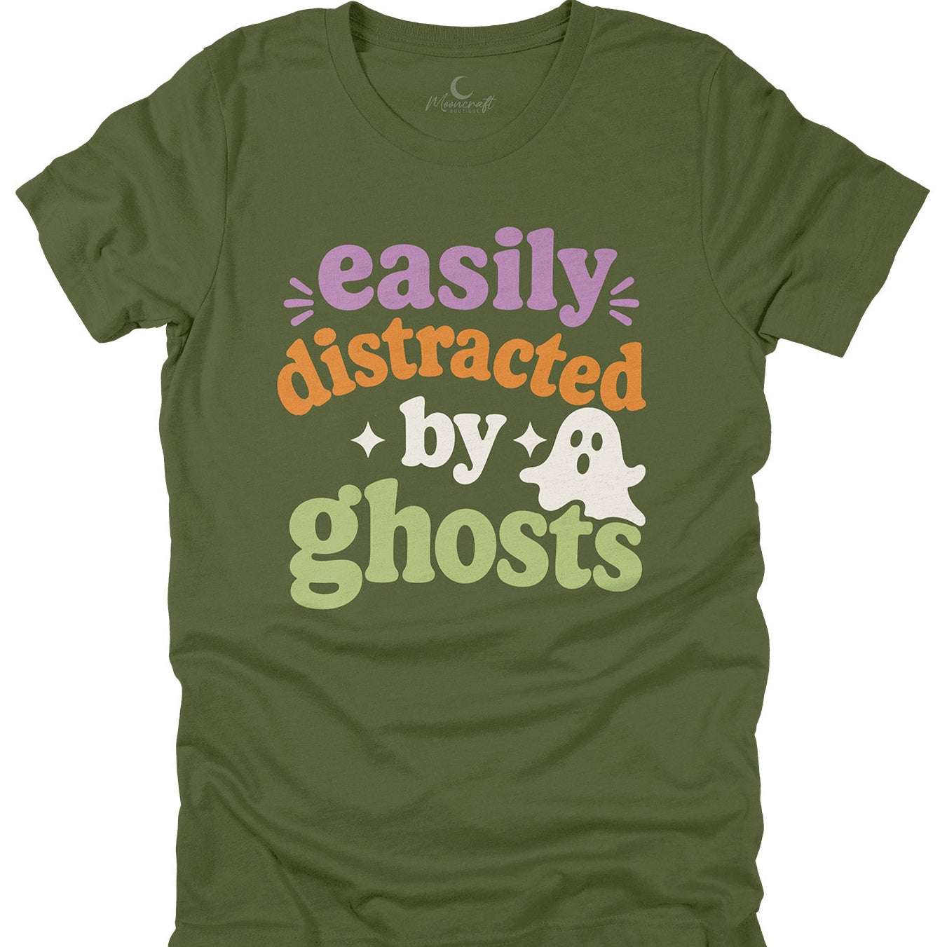 An olive green short-sleeve t-shirt with a retro-style graphic that reads 'easily distracted by ghosts' in purple, orange, light green, and white lettering, accompanied by a small white ghost illustration.