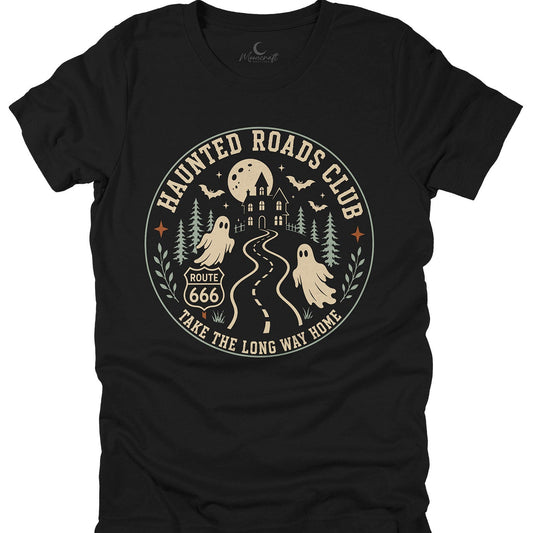 A black short-sleeve t-shirt with a circular vintage-style graphic on the front. The graphic features a haunted house, a full moon, bats, pine trees, two ghosts, a winding road, and the text 'HAUNTED ROADS CLUB' and 'TAKE THE LONG WAY HOME' in beige.