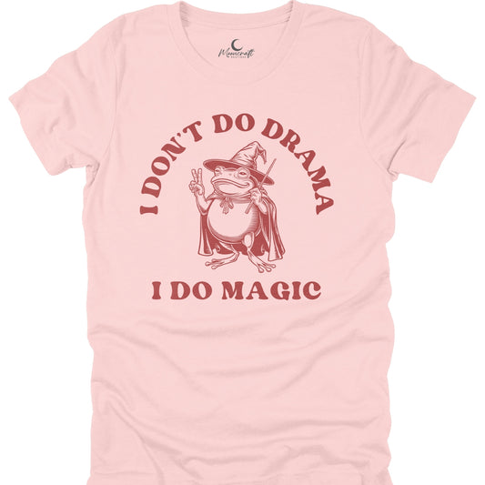 Pink t-shirt with a graphic of a frog in a witch hat and cape, text 'I Don't Do Drama I Do Magic', and a brand logo on a white background.