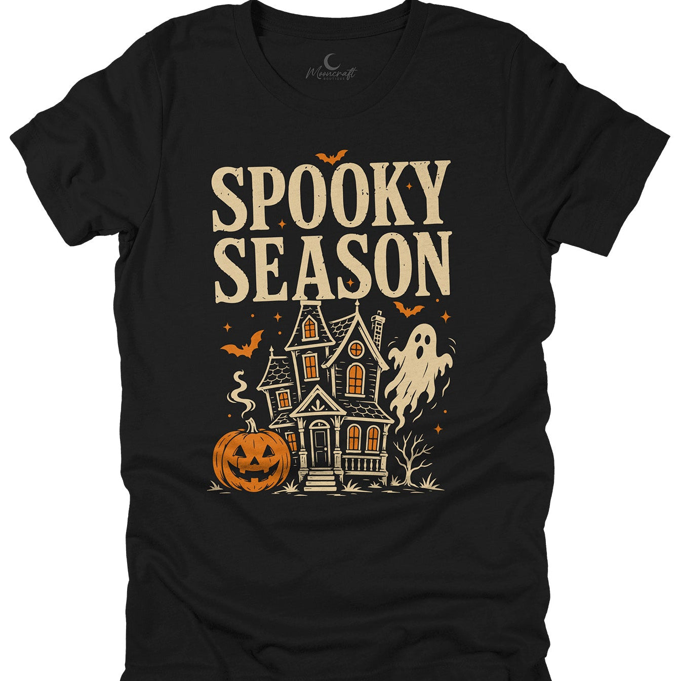 A black short-sleeve t-shirt with a 'Spooky Season' Halloween graphic, featuring a haunted house, jack-o'-lantern, ghost, and bats in beige and orange, displayed on a solid white background.
