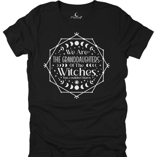 Black t-shirt with the text 'We Are The Granddaughters of The Witches' printed in white, surrounded by a geometric design featuring moons and stars.